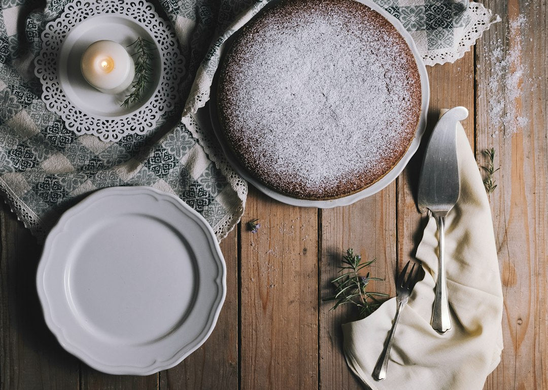 Pie on white ceramic plate beside white tealight candle and cake server