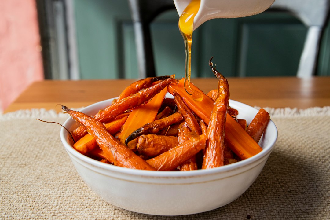 A white bowl filled with carrots sitting on top of a table
