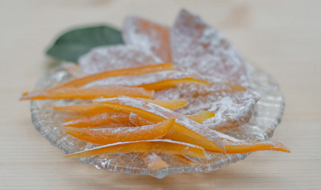 A glass bowl filled with sugar and orange peels