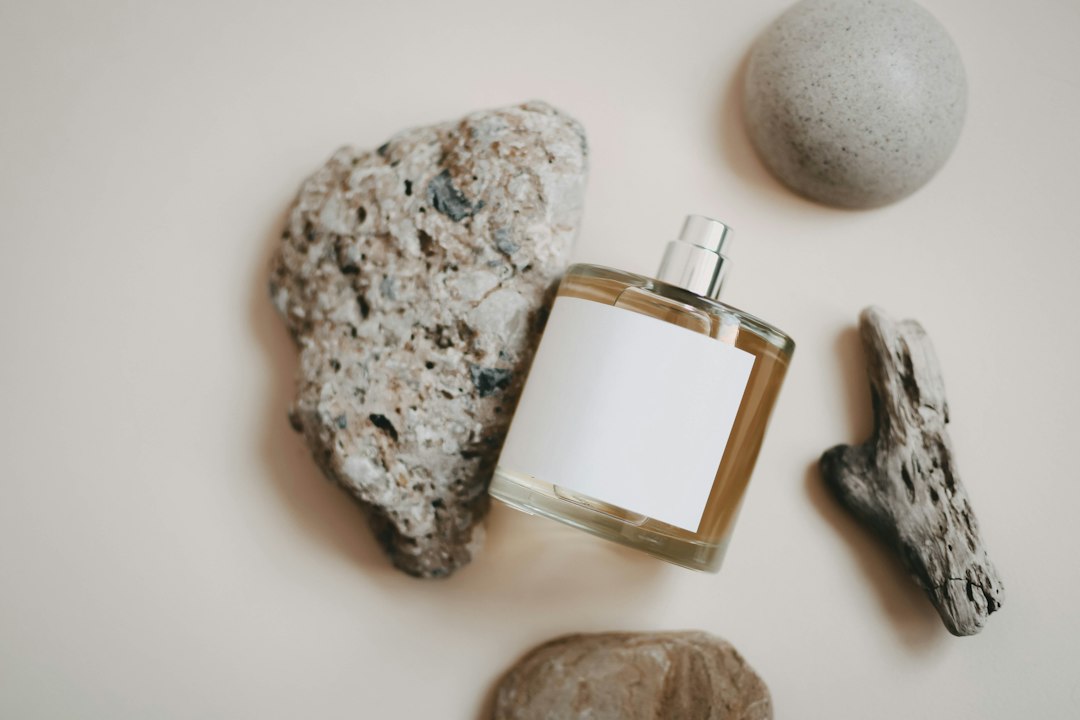 A bottle of cologne next to rocks and a rock