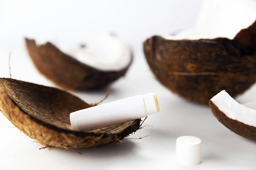 Lip balm in coconut shell halves on white background
