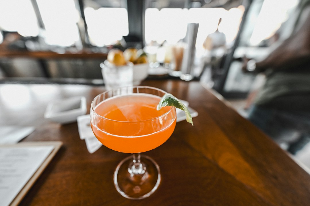 Orange cocktail with lime garnish on a wooden bar