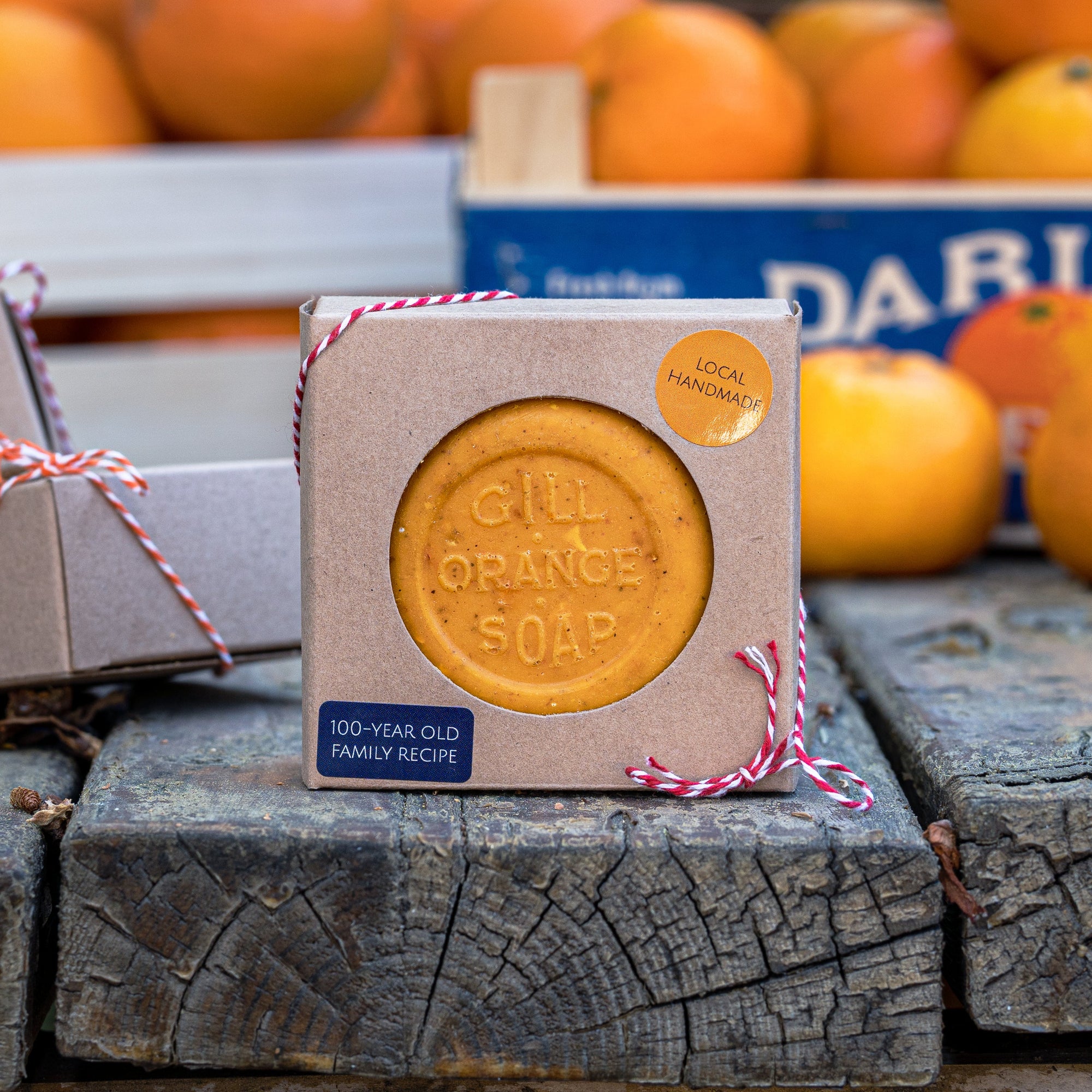 Box of Gill Orange Soap on wooden blocks with oranges in the background